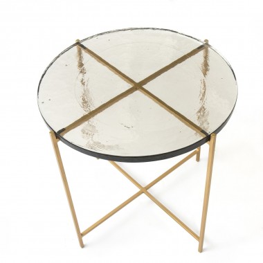 Mesa auxiliar con sobre de vidrio rústico y patas metálica lacadas en dorado.
