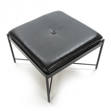 Taburete bajo de polipiel negra con patas metálicas negras.
