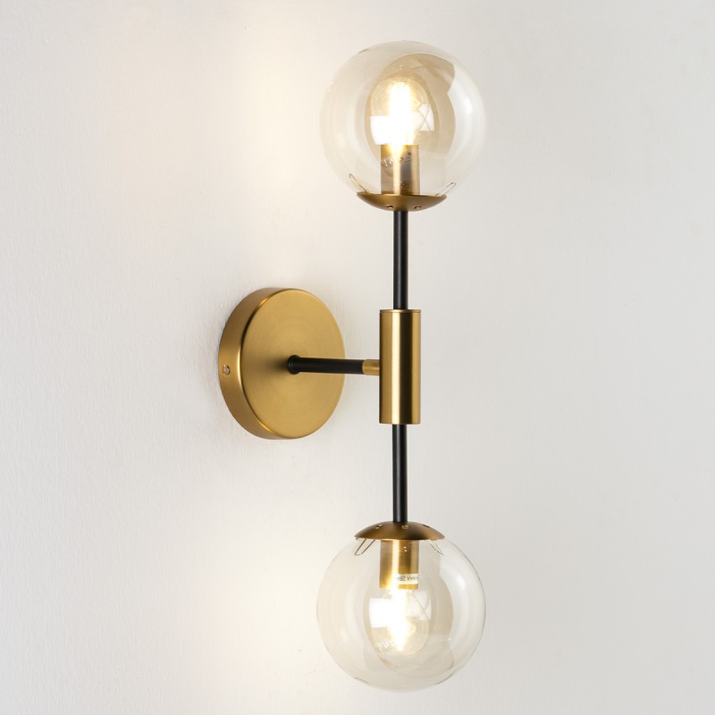 Aplique de pared metálico en negro y dorado con dos esferas de vidrio tintado en color ámbar.